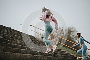 Active women in sportswear running up stairs outdoors for fitness and health