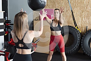 Active women throwing fitness ball to each other at gym