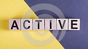 ACTIVE word on wooden cubes on yelloe and gray background