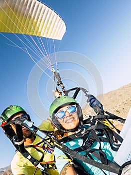 Active young adult people woman enjoy paraglide activity fliying in the sky with professional pilote in the back - cheerful happy photo