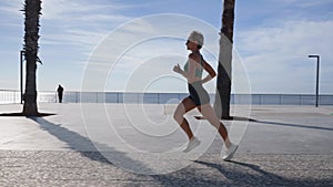 Active young beautiful woman running on the promenade along the seaside.