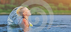 Active young blonde woman waving hair splashing water in river. Beautiful healthy lady relax and laughing, raising head out of the