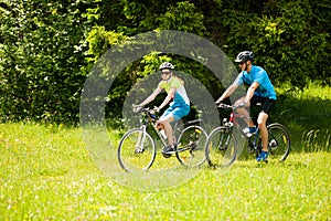 ACTIVE Young couple biking on a forest road in mountain on a spring day