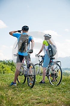 ACTIVE Young couple biking on a forest road in mountain on a spring day