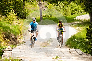 ACTIVE Young couple biking on a forest road in mountain on a spring day