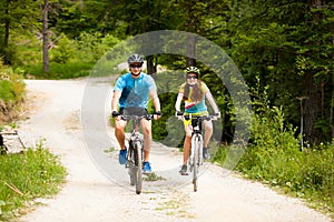 ACTIVE Young couple biking on a forest road in mountain on a spring day