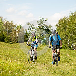 ACTIVE Young couple biking on a forest road in mountain on a spring day