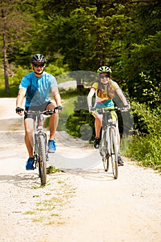 ACTIVE Young couple biking on a forest road in mountain on a spring day