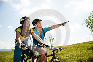 ACTIVE Young couple biking on a forest road in mountain on a spring day