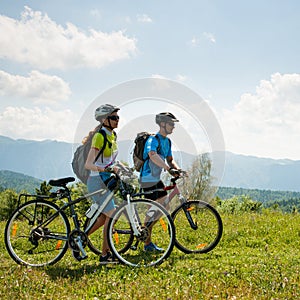 ACTIVE Young couple biking on a forest road in mountain on a spring day