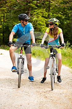 ACTIVE Young couple biking on a forest road in mountain on a spring day