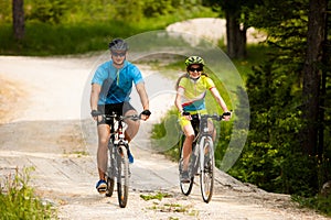 ACTIVE Young couple biking on a forest road in mountain on a spring day