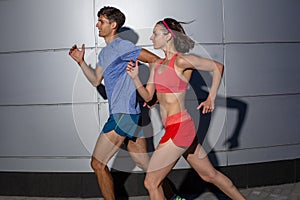 Active young couple jogging side by side in an urban street during their daily workout in a health and fitness concept