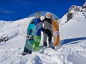 Active young couple poses with their snowboards high in the beautiful Rockies.