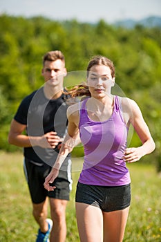 Active young couple running cross country in nature on a fores photo