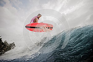 Active young girl jumping on the orange wakeboard