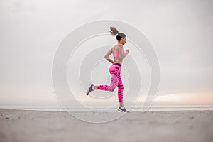 Active young girl running over the sea coast in the morning