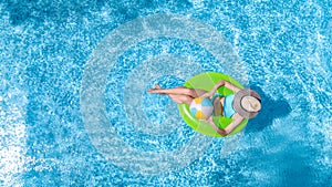 Active young girl in swimming pool aerial drone view from above, teenager relaxes and swims on inflatable ring donut and has fun