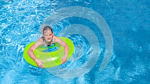 Active young girl in swimming pool aerial top view from above, child relaxes and swims on inflatable ring donut and has fun