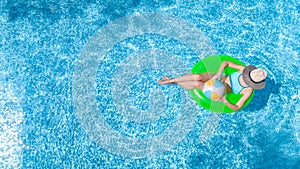 Active young girl in swimming pool aerial top view from above, child relaxes and swims on inflatable ring donut and has fun