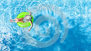 Active young girl in swimming pool aerial top view from above, child relaxes and swims on inflatable ring donut and has fun