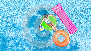 Active young girl in swimming pool aerial top view from above, child relaxes and swims on inflatable ring donut and has fun