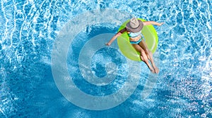 Active young girl in swimming pool aerial top view from above, teenager relaxes and swims on inflatable ring donut and has fun