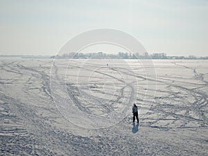 Active young man cross-country skiing on huge frozen river