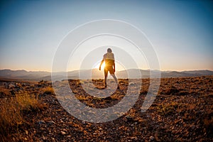 An active young man feels free. A confident man stands on a mountain against the background of a sunset. Experience freedom in the