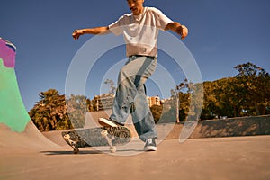 Active young man riding skateboard in skate park on sunny day. Extreme sport concept