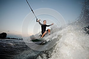 Active and young man riding on a wake board at the evening