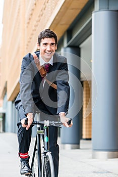 Active young man smiling while riding utility bicycle to his wor