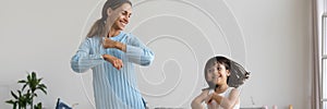 Active young mother little daughter dancing listening music having fun