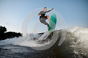 Active and young wake surfer jumping on a wake board down the river