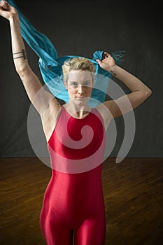 Young woman in red unitard waving a blue scarf.