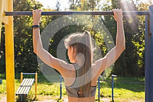 Active and young woman doing pullups.