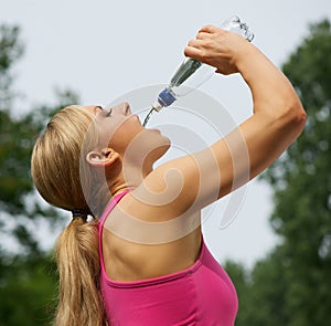 Active young woman drinking water after exercise