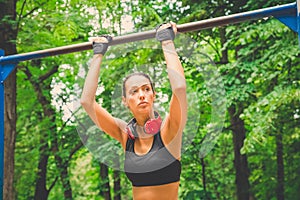 Active and young woman with headphones doing pullups