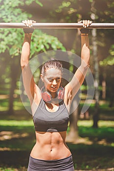 Active and young woman with headphones doing pullups