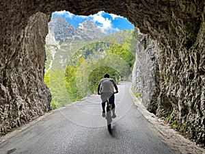Active young woman on a scenic mountain bike ride pedals out of a dark tunnel.