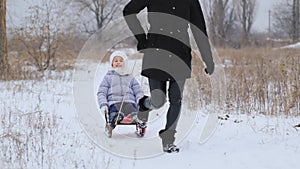 Actively spending the Christmas holidays with the family. Mother rides her daughter on a sleigh in the park in winter.