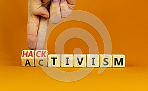 Activism or hacktivism symbol. Businessman turns wooden cubes and changes the word Activism to Hacktivism. Beautiful orange table photo