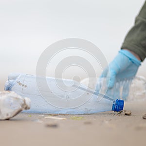 The activist collects garbage and plastic bottles on the seashore. Caring for the purity of nature. Environmental protection.