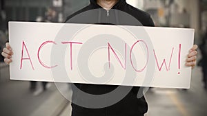 Unknown activist holds a placard with ACT NOW text photo