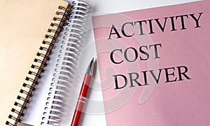 ACTIVITY COST DRIVER text on pink paper with notebooks