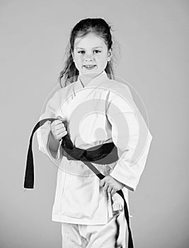 Activity and sport. Strong and confident kid. Girl little child in white kimono with belt. Karate fighter ready to fight