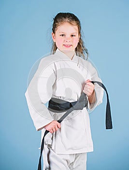 Activity and sport. Strong and confident kid. Girl little child in white kimono with belt. Karate fighter ready to fight