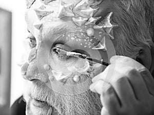 Actor applying make up on face. Senior male model in backstage