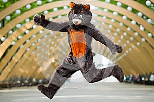 actor dressed as bear jumps under the arch of photo