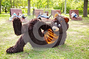 actor dressed as bear lies on grass in park and